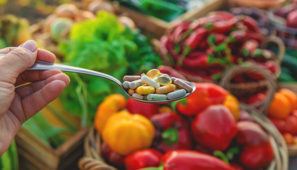 Vitamins and supplements in a spoon with vegetables. Selective focus.